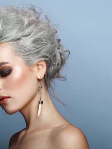 vrouw van middelbare leeftijd met grijs kort haar met slag tegen blauwe achtergrond