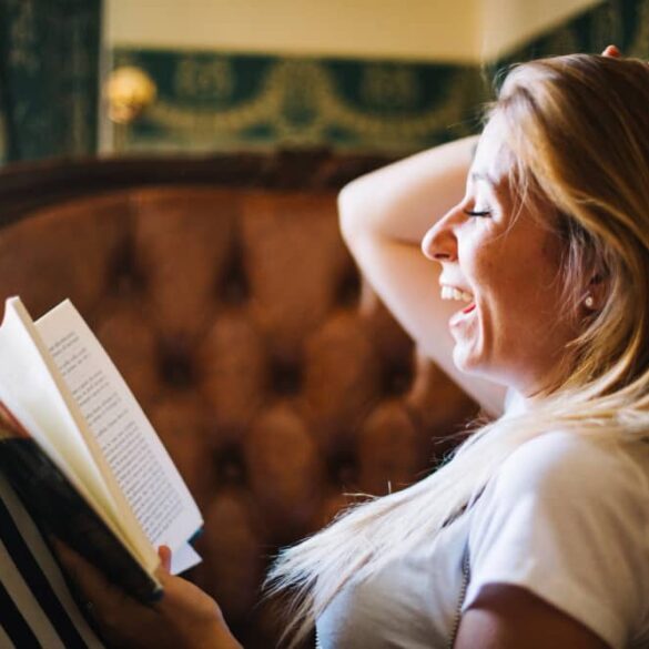 vrouw leest boek op bank en kijkt blij
