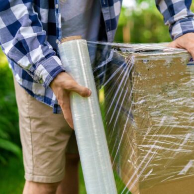 man brengt wikkelfolie aan om pakket