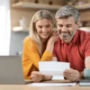 middelbaar stel achter laptop met document