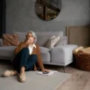 oudere vrouw zit comfortabel op houten vloer met kleed